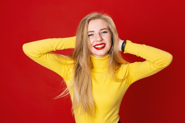 Donna in un maglione giallo che tiene la sua testa su sfondo rosso