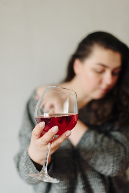 Donna in un maglione grigio con un bicchiere di vino rosso