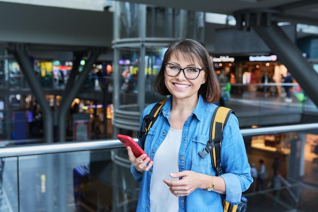 Donna in un moderno edificio della stazione di trasporto cittadino con smartphone Donna che utilizza una rete di connessione internet veloce per il servizio di biglietteria online percorso di trasporto dell'orario dell'applicazione mobile