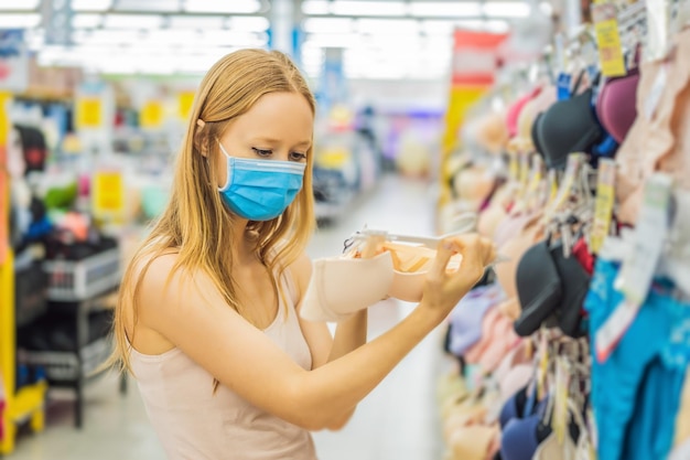 Donna in un negozio di abbigliamento con mascherina medica a causa di un coronovirus La quarantena è finita ora puoi andare al negozio di abbigliamento