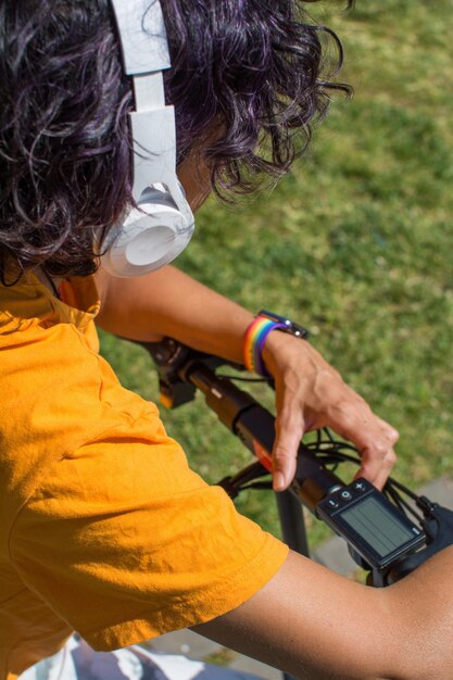 Donna In Un Parco Ad Ascoltare Musica Con Le Cuffie Accanto A Uno Scooter Elettrico.