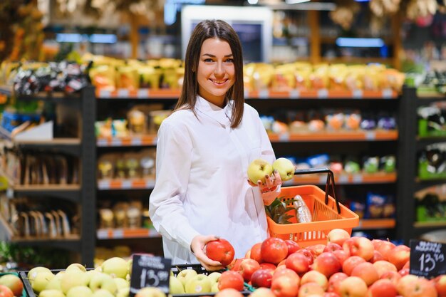 Donna in un supermercato allo scaffale di verdure che fa la spesa, sta scegliendo