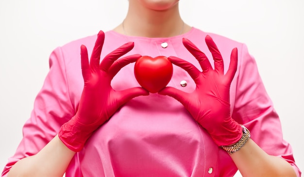 Donna in un'uniforme medica rosa che tiene un cuore in una mano