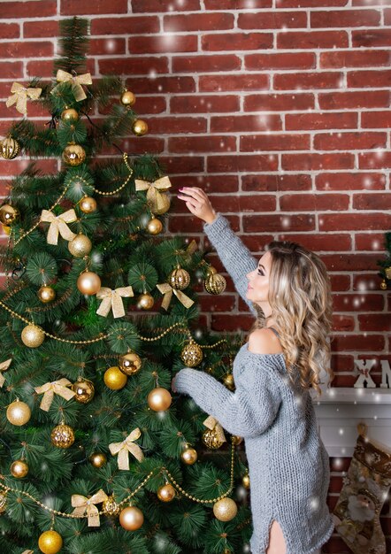 donna in un vestito a maglia decora un albero di Natale