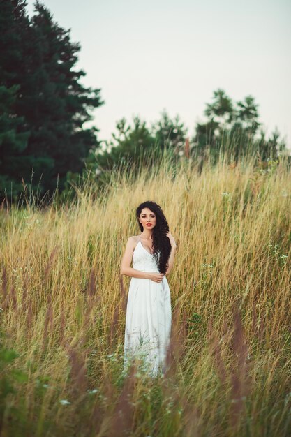 Donna in un vestito bianco che posa in un campo