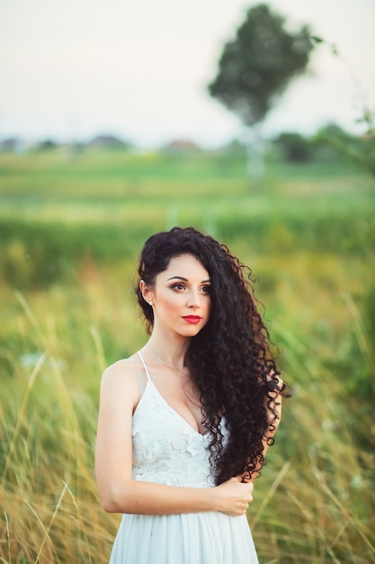 Donna in un vestito bianco che posa in un campo