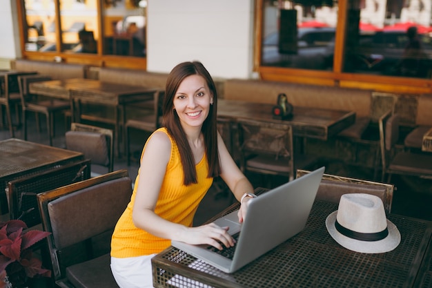 Donna in una caffetteria all'aperto di strada seduta al tavolo che lavora su un moderno computer portatile, rilassarsi al ristorante durante il tempo libero