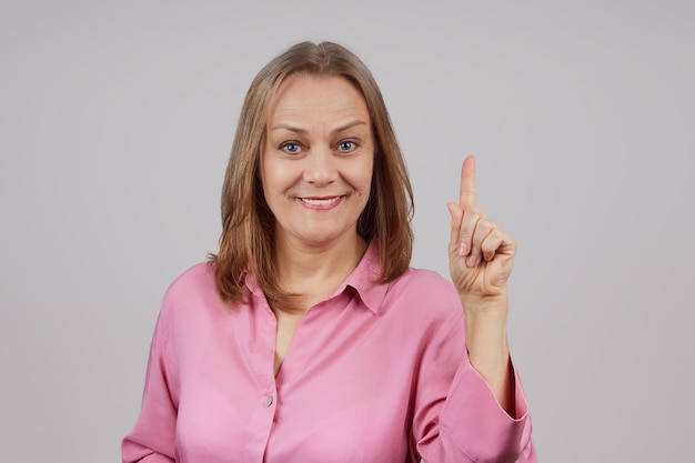 donna in una camicia rosa tiene la mano con il dito indice in alto