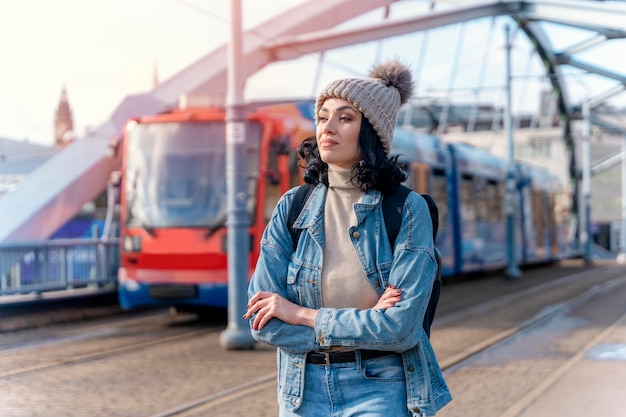 donna in una giacca di jeans sta parlando al telefono e in attesa di un autobus del tram Foto di stile di vita