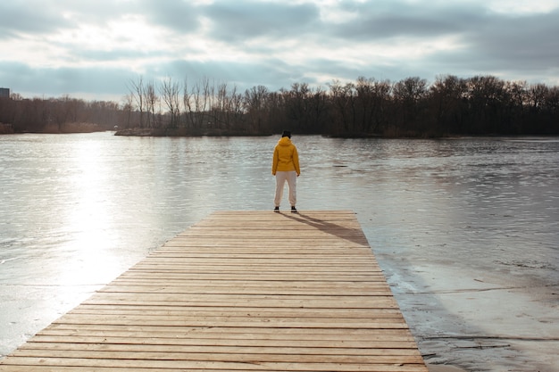 Donna in una giacca invernale gialla contro un fiume