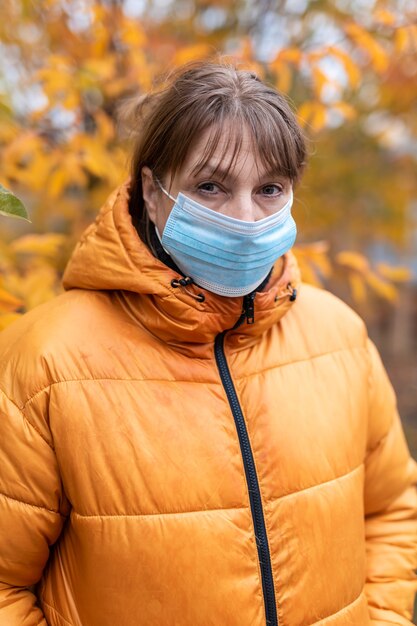 Donna in una maschera medica nel parco d'autunno