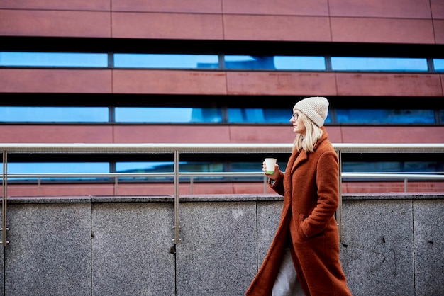 Donna in una strada cittadina con una tazza di caffè