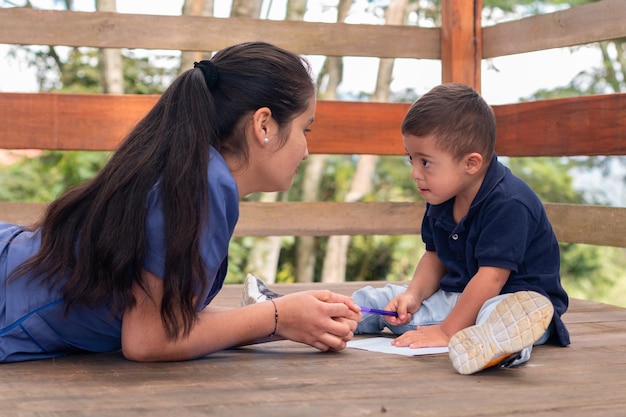 Donna in uniforme blu che insegna a scrivere a un bambino con sindrome di Down Terapia occupazionale per bambini