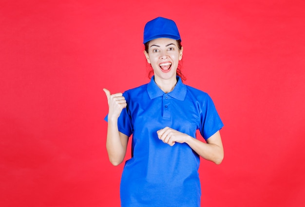 Donna in uniforme blu che mostra all'indietro.