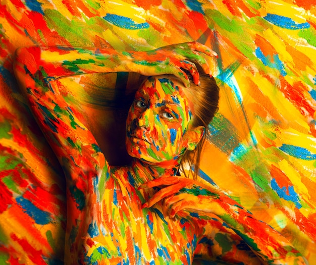 Donna in vernice bodyart vicino alla parete multicolore