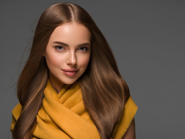 Donna in vestiti a maglia giallo autunno inverno stile capelli lunghi. Colore di sfondo grigio.