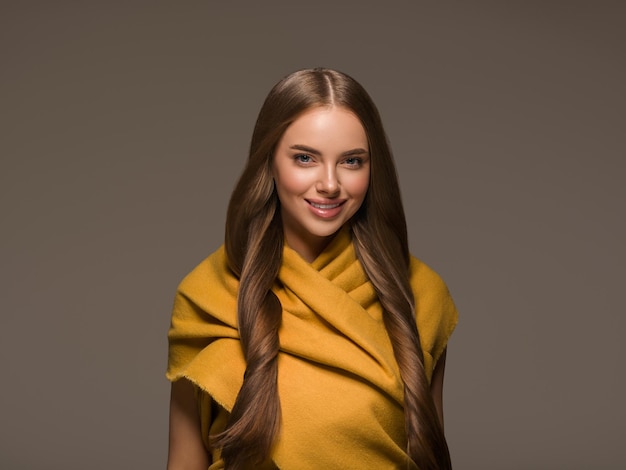 Donna in vestiti a maglia giallo autunno inverno stile capelli lunghi. Colore di sfondo marrone