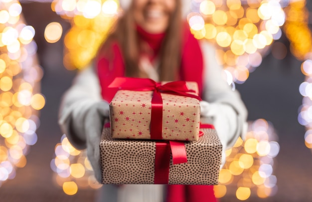 Donna in vestiti caldi che mostrano i regali di Natale