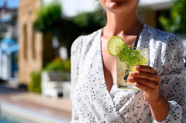 Donna in vestito bianco che beve un cocktail mojito