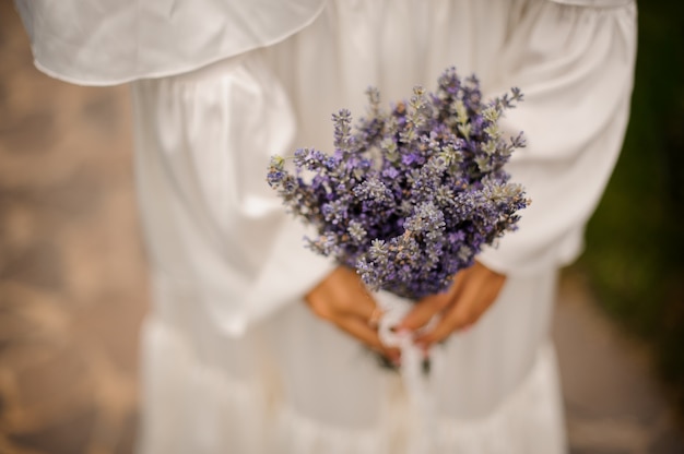 Donna in vestito bianco che tiene un mazzo di lavanda