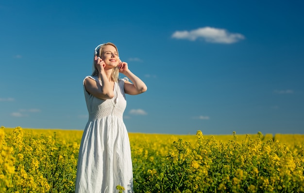 Donna in vestito con le cuffie nel campo di colza