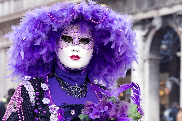 Donna in vestito di carnevale veneziano nella via della città. Colore viola. Martedì grasso. Carnevale tradizionale a Venezia