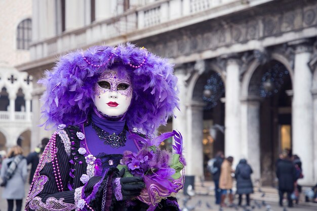 Donna in vestito di carnevale veneziano nella via della città. Colore viola. Martedì grasso.