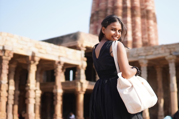 Donna in vestito nero che guarda indietro con la borsa della holding