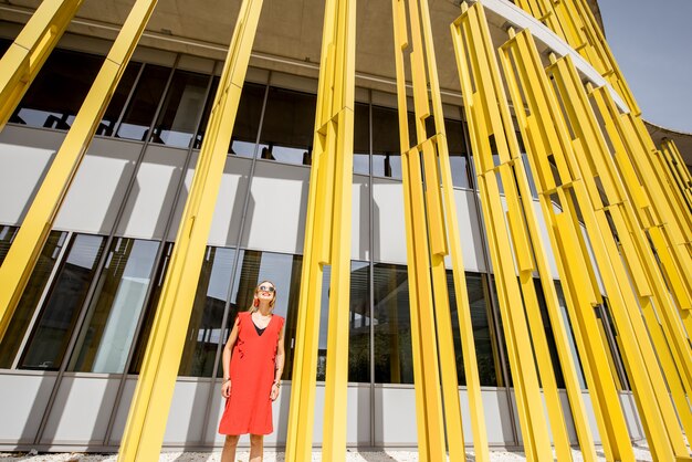 Donna in vestito rosso sui precedenti gialli moderni della parete dell'edificio. Composizione geometrica astratta