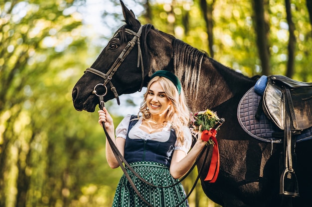 Donna in vestito tradizionale che cammina con un cavallo nella foresta