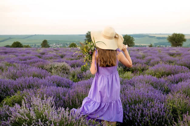 Donna in vestito viola e cappello nel giacimento della lavanda