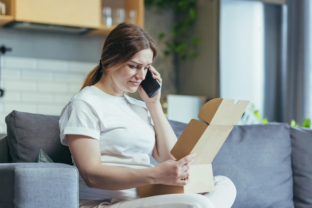 Donna incinta a casa arrabbiata e delusa ha ricevuto il pacco sbagliato una donna sul divano che parla al telefono