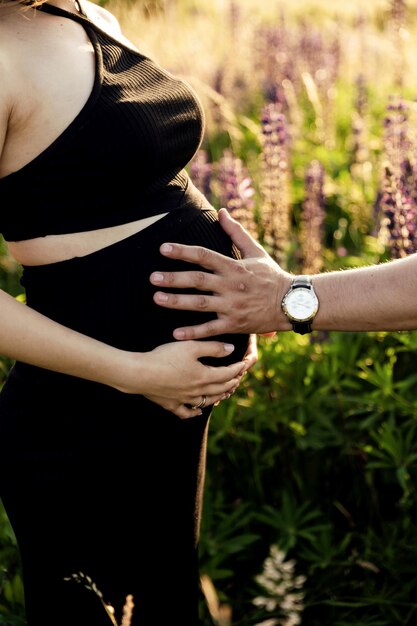 donna incinta abbraccia il suo stomaco con le mani closeup di mani sdraiate su una pancia incinta coppia incinta in attesa di un neonato