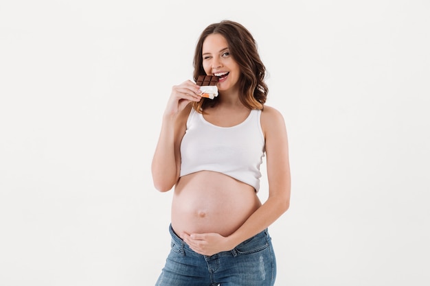 Donna incinta allegra che mangia cioccolato