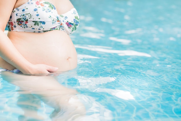 Donna incinta asiatica con grande pancia. Rilassatevi ed esercitatevi in piscina