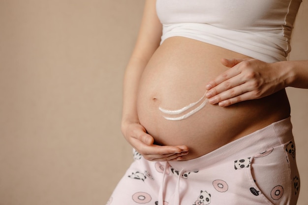donna incinta che applica crema idratante sulla pancia