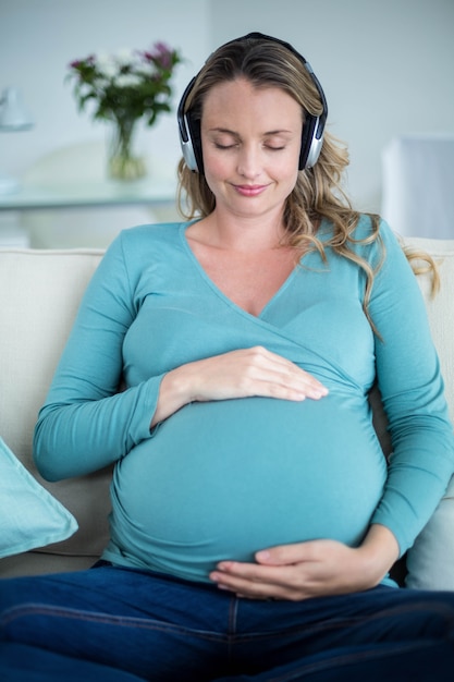 Donna incinta che ascolta la musica sul divano