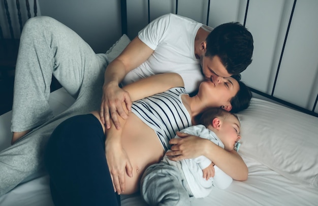 Donna incinta che bacia il suo partner mentre il figlio dorme