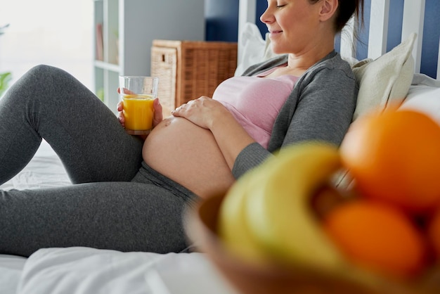 Donna incinta che beve succo appena spremuto a letto