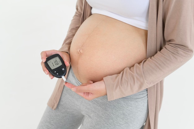 Donna incinta che controlla il livello di zucchero nel sangue utilizzando un misuratore digitale della glicemia