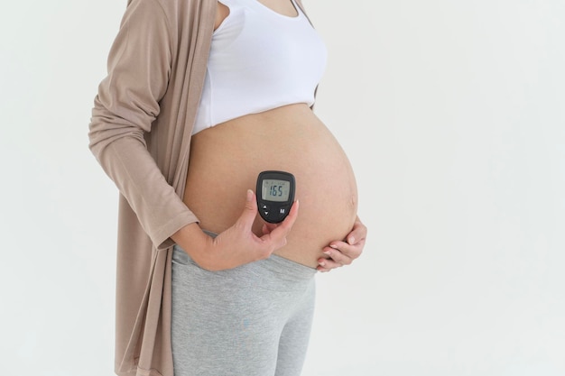 Donna incinta che controlla il livello di zucchero nel sangue utilizzando un misuratore digitale della glicemia