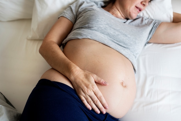 Donna incinta che dorme sul letto