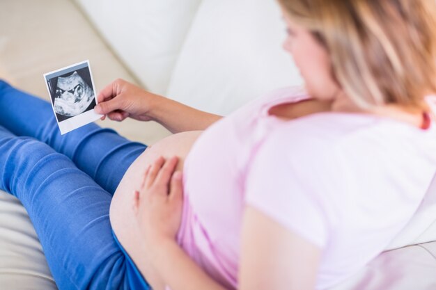 Donna incinta che esamina le ecografie e che tocca la sua pancia