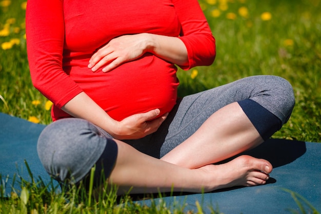 Donna incinta che fa asana sukhasana all'aperto