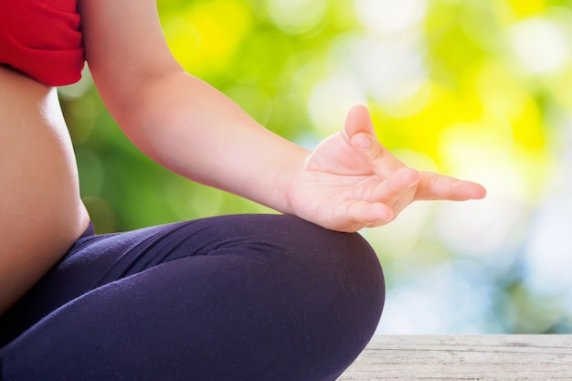 Donna incinta che fa yoga con la superficie del bokeh della natura