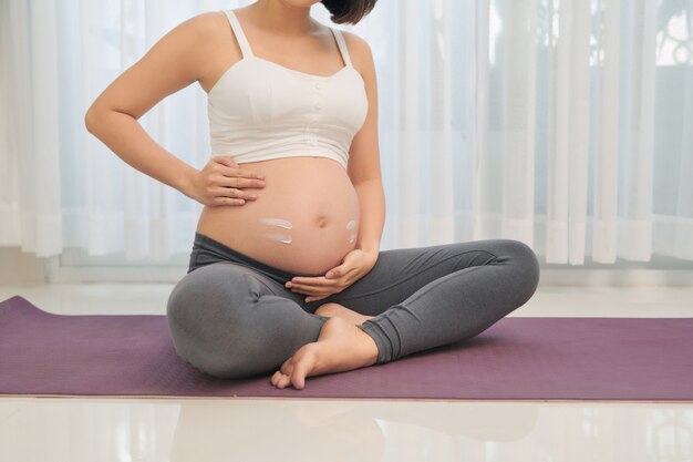 Donna incinta che fa yoga nel soggiorno