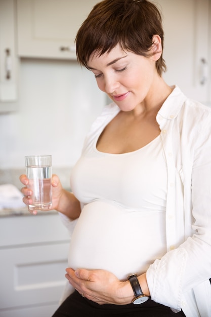 Donna incinta che ha un bicchiere d&#39;acqua