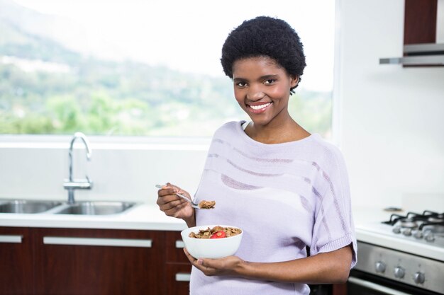 Donna incinta che mangia cereale in cucina