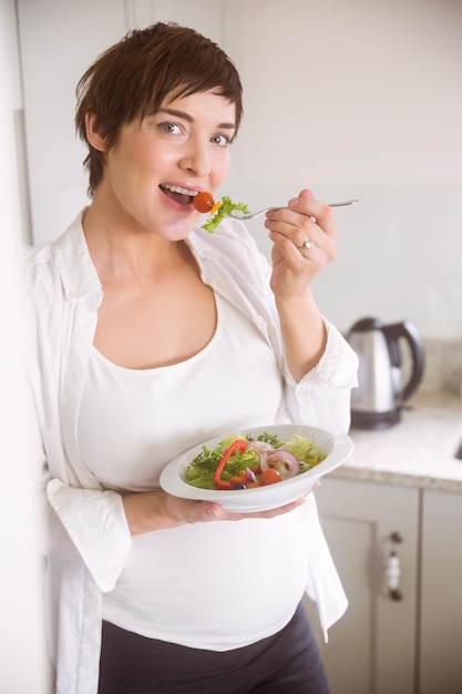 Donna incinta che mangia ciotola di insalata