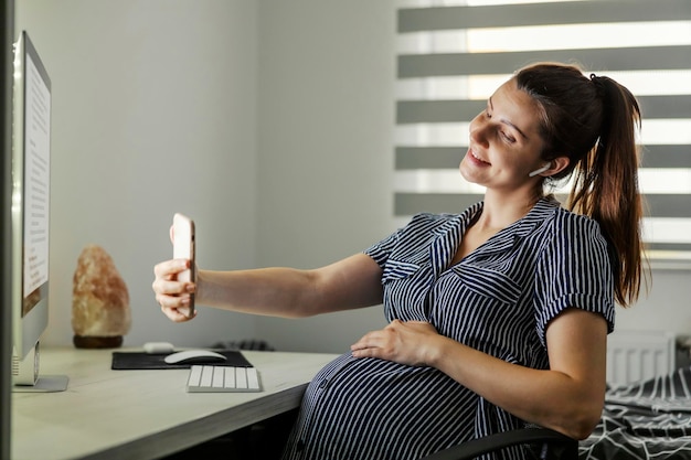 Donna incinta che scatta una foto e utilizza un telefono in ufficio